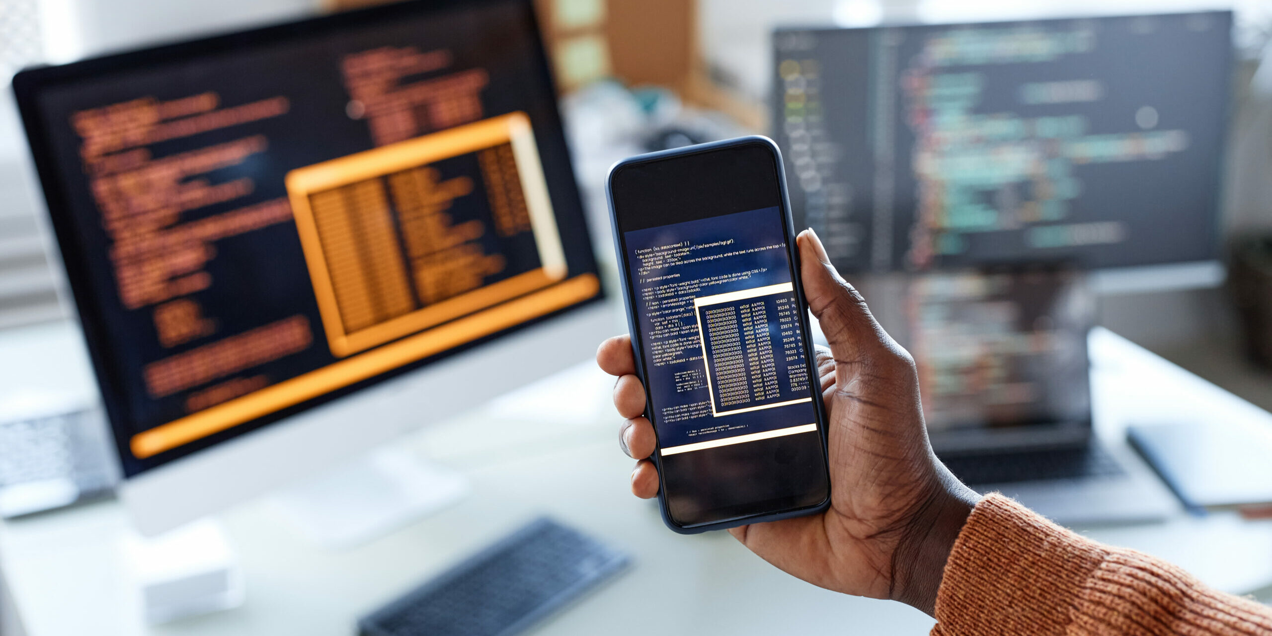 Hand of developer showing smartphone with code of new app on screen